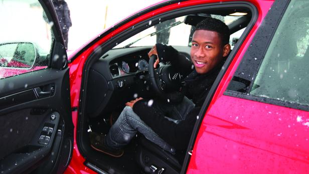 David Alaba sitzt lächelnd in einem roten Auto.