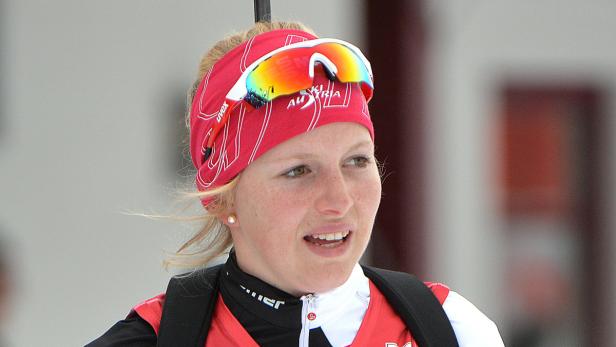 Porträt einer Biathletin mit rotem Stirnband und Skibrille.