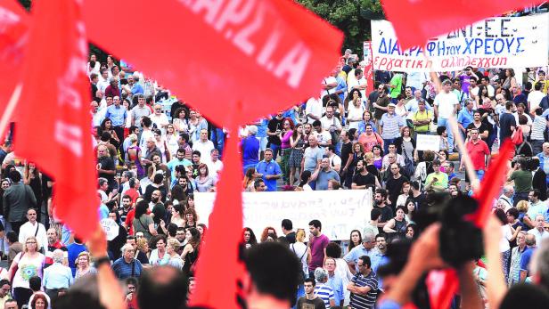 Eine Menschenmenge demonstriert mit roten Fahnen und Transparenten.