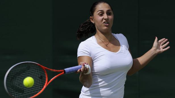 Eine Tennisspielerin schlägt einen Ball mit ihrem Schläger.