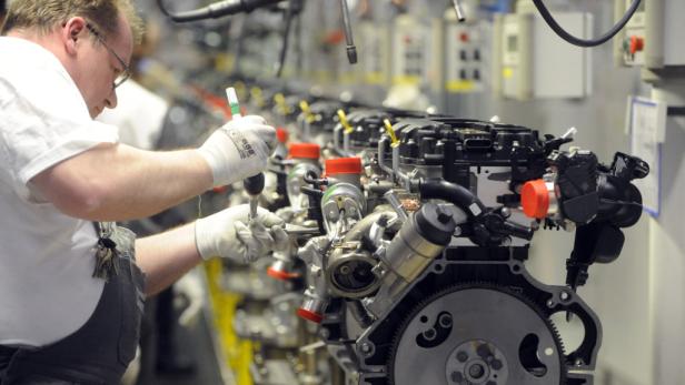 Ein Arbeiter montiert in einer Fabrik einen Motor an der Produktionslinie.
