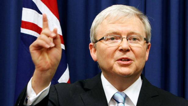 Kevin Rudd gestikuliert vor der australischen Flagge.
