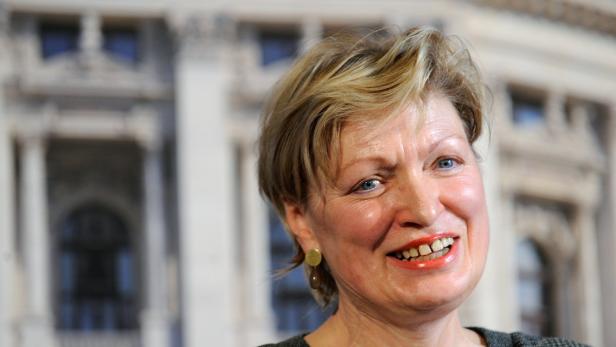BURGTHEATER: KARIN BERGMANN Nahaufnahme einer lächelnden Frau mit blonden Haaren vor einem Gebäude.