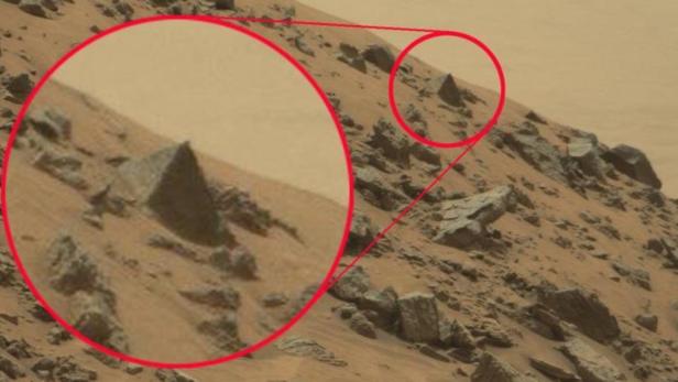 Eine Hügellandschaft auf dem Mars mit einem pyramidenförmigen Felsen, der rot eingekreist ist.