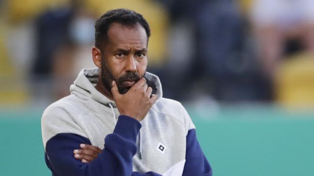 Ein Mann mit verschränkten Armen und nachdenklichem Blick, möglicherweise ein Trainer beim DFB-Pokalspiel Dynamo Dresden gegen Hamburger SV.