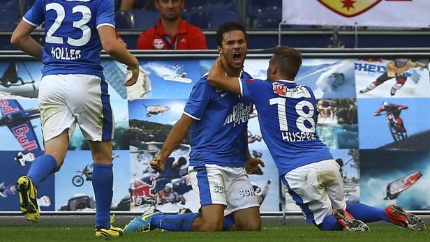 Zwei Fußballspieler in blauen Trikots feiern ein Tor auf dem Rasen.