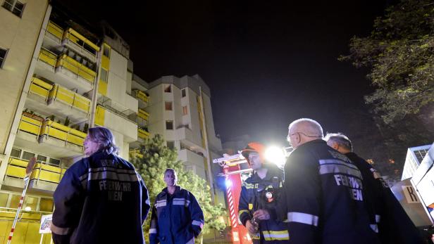 Feuerwehrleute stehen nachts vor einem Wohnhaus in Wien.