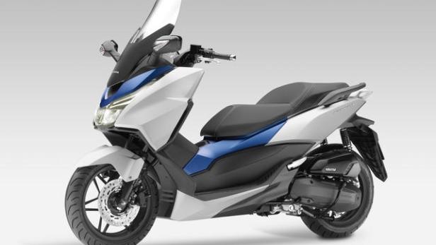 Ein weißer und blauer Honda Forza Motorroller steht vor einem neutralen Hintergrund.