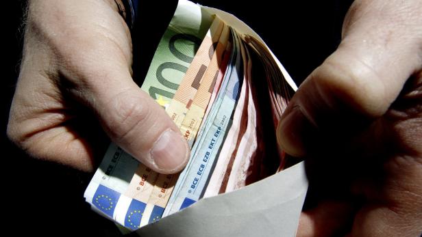 Eine Hand hält einen Umschlag gefüllt mit Euro-Banknoten.