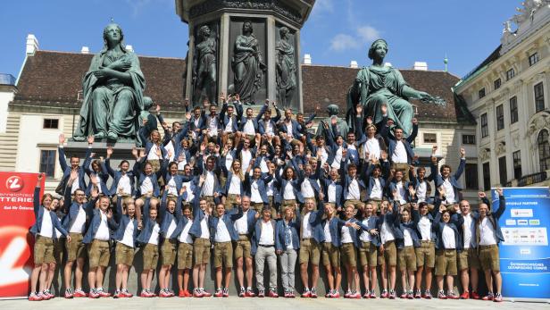 Eine große Gruppe von Menschen in Tracht posiert vor dem Denkmal von Kaiser Franz Joseph I. in Wien.