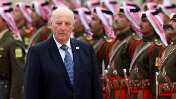 König Harald V. von Norwegen vor einer Reihe von Soldaten in Uniformen.