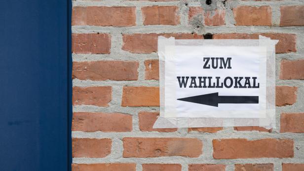 Zettel mit der Aufschrift "Zum Wahllokal" hängt an einer Wand. 