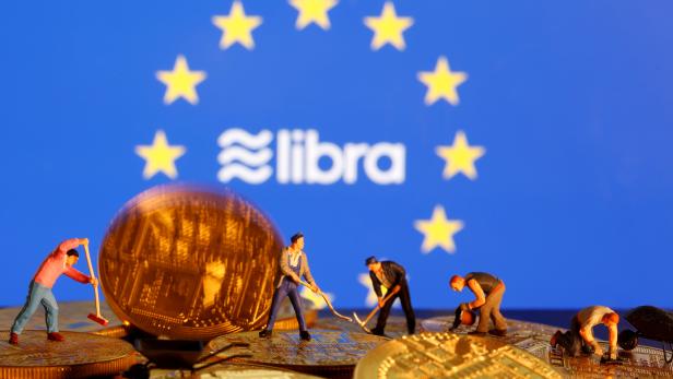 FILE PHOTO: Small toy figures are seen on representations of the virtual currency before the displayed European Union flag and the Facebook Libra logo in this illustration picture