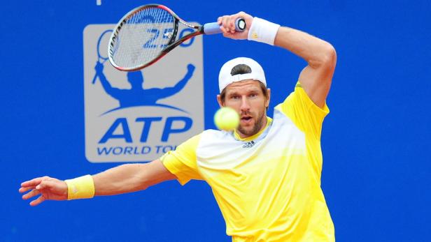 Ein Tennisspieler schlägt einen Ball vor einem blauen ATP-Hintergrund.