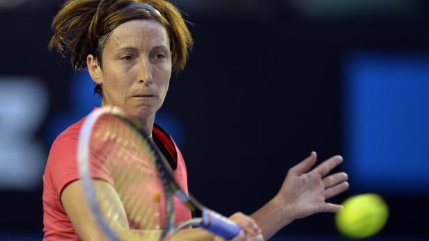 Eine Tennisspielerin schlägt einen gelben Tennisball.