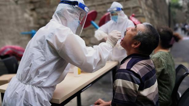 Medical worker collects swab from a man to conduct free nucleic acid tests for residents in the residential compound in Urumqi