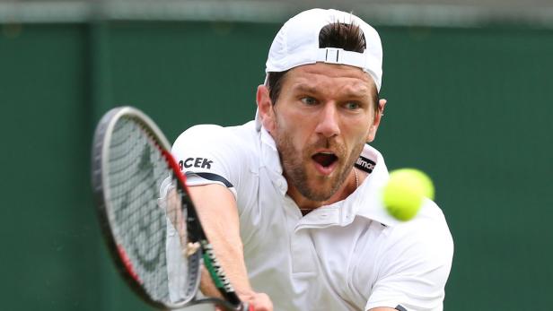 Ein Tennisspieler schlägt einen Ball mit seinem Schläger.