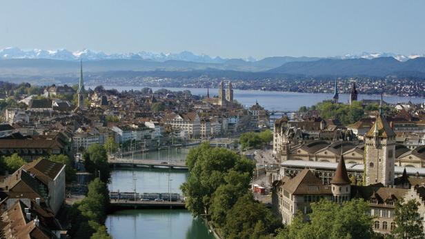 Ein Blick über Zürich mit dem Fluss Limmat und den Alpen im Hintergrund.