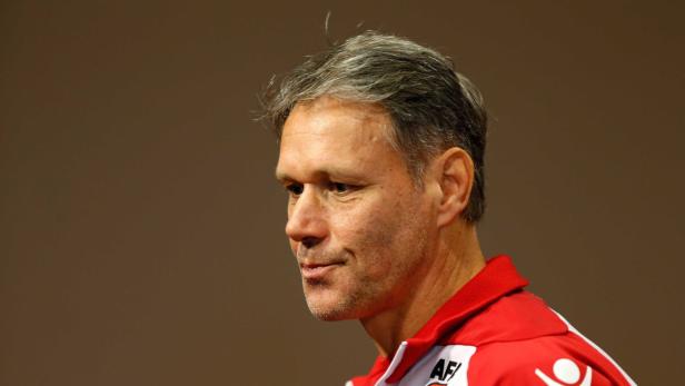 Ein Mann mit grau meliertem Haar in einem rot-weißen Sporttrikot blickt nach links.