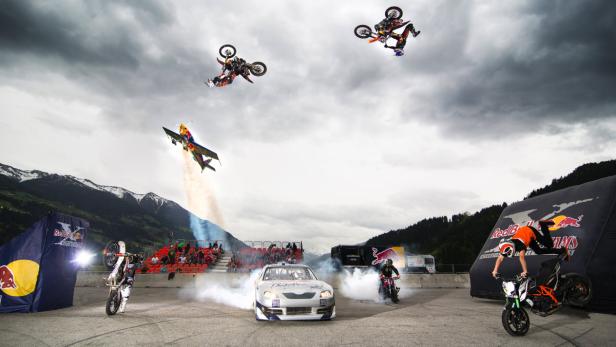 A Nascar drifts beneath FMX-rider in backflip position, while air race pilot Hannes Arch flies over and stunt riders perform below in the lead up of the 8th &quot;KINI Fullgas Day&quot; motorsports exhibition on Wednesday, May 1st 2013, in Schlitters, Zillertal, Tyrol. Thousands of spectators enjoyed the motor sports show program and air show during this extraordinary motor sports exhibition annually taking place on May 1st, featuring Formula1 cars, rally trucks and KTM bikes (among others). Free image for editorial usage only: Photo by Johannes Sautner.