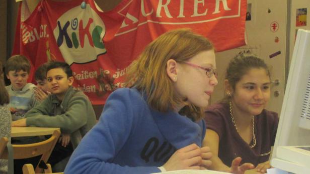 Schüler arbeiten gemeinsam an einem Computer in einem Klassenzimmer.