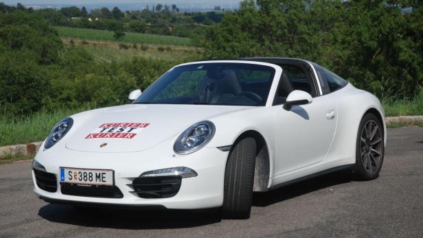 Ein weißer Porsche Targa steht auf einer asphaltierten Straße.