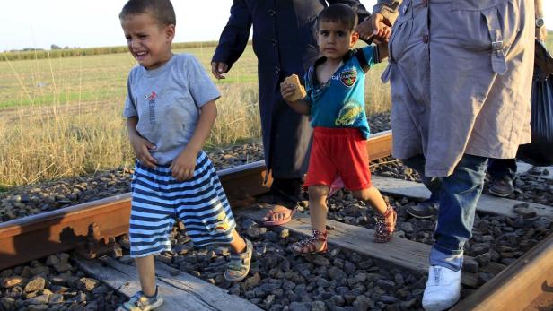 A migrant boy cries as he walks on a railway track