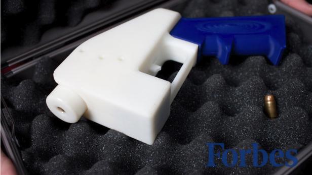 Eine weiße, blaugriffige Pistole und eine Patrone liegen in einem Koffer mit Schaumstoffeinlage.