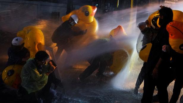 Demonstrators use inflatable rubber ducks as shields to protect themselves from water cannons during an anti-government protest, outside the parliament in Bangkok