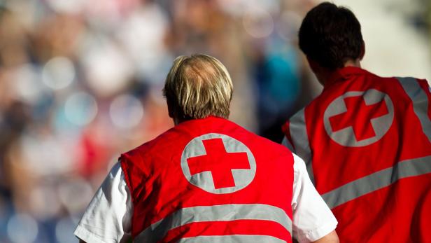 Zwei Sanitäter mit roten Westen und dem Schweizer Kreuz auf dem Rücken stehen im Einsatz.