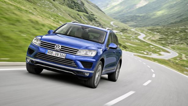 Ein blauer VW Touareg fährt auf einer kurvenreichen Bergstraße.