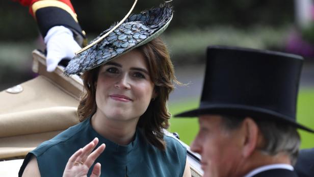 Prinzessin Eugenie winkt mit einem Federhut auf dem Weg in einer Kutsche.