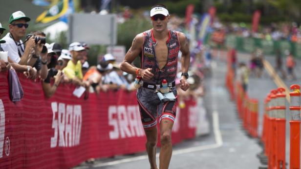 Ein Triathlet läuft während eines Rennens an Zuschauern vorbei.
