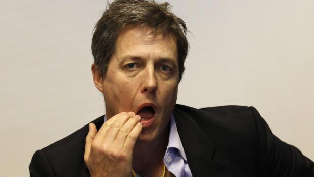 Hugh Grant mit der Hand vor dem Mund.