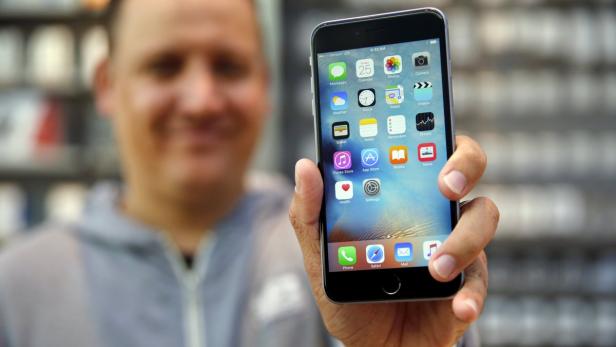 Eine Person hält ein iPhone mit dem Homescreen in der Hand.