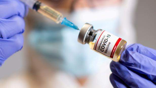 FILE PHOTO: FILE PHOTO: A woman holds a medical syringe and a small bottle labeled "Coronavirus COVID-19 Vaccine