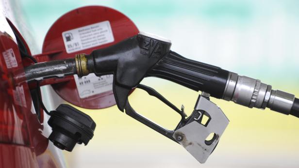 Eine Zapfpistole steckt in einem roten Auto.