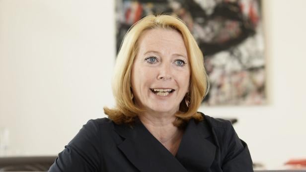 Eine blonde Frau mit blauem Blazer lächelt in die Kamera.