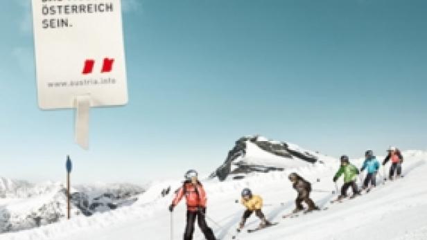 Eine Gruppe von Skifahrern fährt einen schneebedeckten Hang hinunter, beworben mit einem Schild für Österreich.