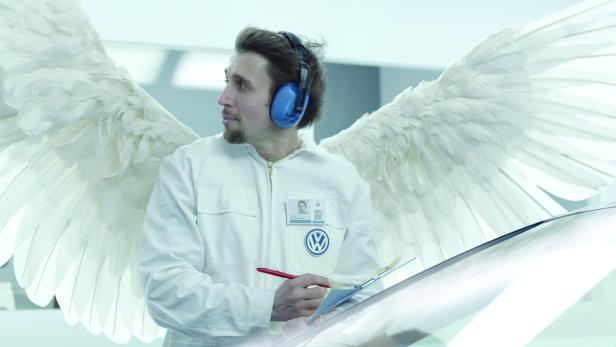 Ein VW-Mitarbeiter mit Flügeln und Kopfhörern macht sich Notizen.