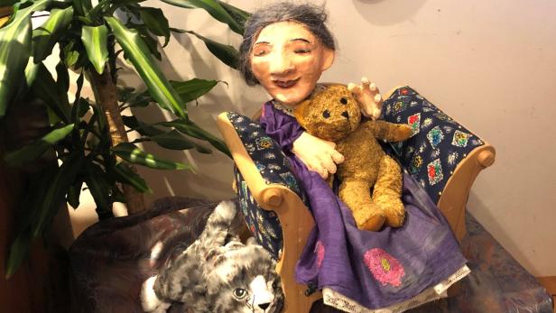 Die Omama sitzt mit ihrem alten Teddy im Sessel und denkt an schöne Erlebnisse