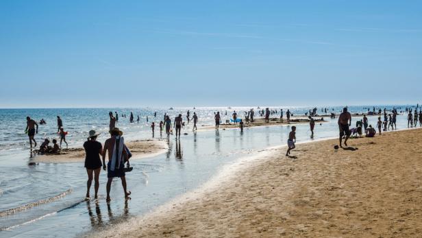 Ein sonniger Tag an einem belebten Strand mit vielen Menschen.