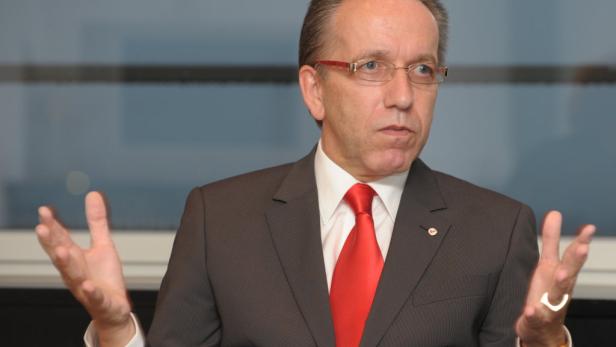 Ein Mann mit Brille, Anzug und roter Krawatte gestikuliert.