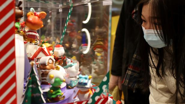 Woman wearing a mask looks at toys on display inside a store of Chinese toy maker Pop Mart at a shopping mall in Beijing