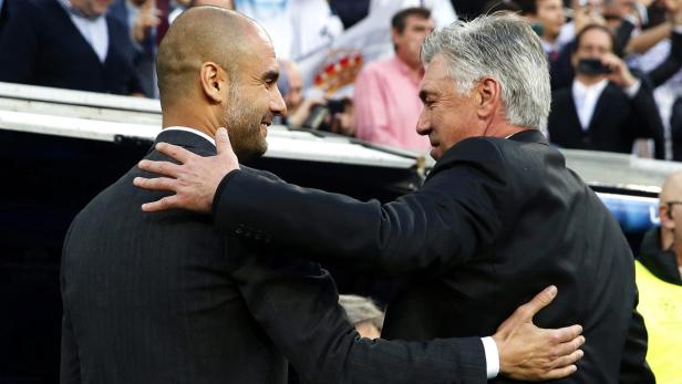 Die Fußballtrainer Pep Guardiola und Carlo Ancelotti umarmen sich.