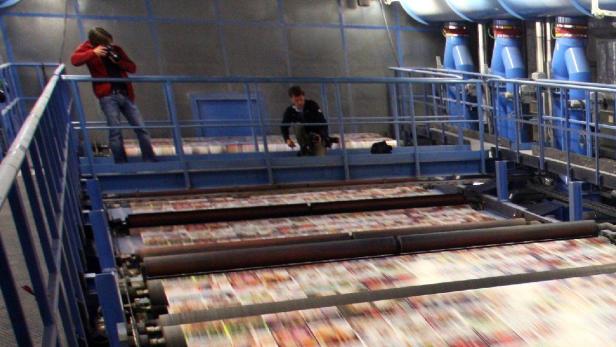 Ein Journalist fotografiert am Montag (22.06.2009) in der Druckerei Prinovis in Nürnberg (Mittelfranken) die mit hoher Geschwindigkeit durch die Trocknung laufenden ungeschnittenen Seiten des neuen Quelle-Kataloges. Dank in Aussicht gestellter Staatsbürgschaften waren die Druckmaschinen in der Nürnberger Druckerei Prinovis am späten Freitagabend angelaufen. Foto: Karl-Josef Hildenbrand dpa/lby +++(c) dpa - Bildfunk+++