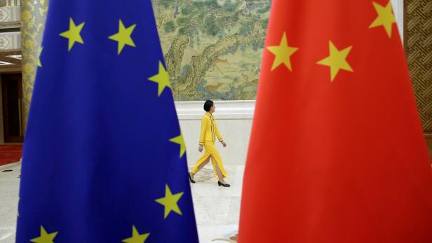 FILE PHOTO: An attendant walks past EU and China flags ahead of the EU-China High-level Economic Dialogue in Beijing