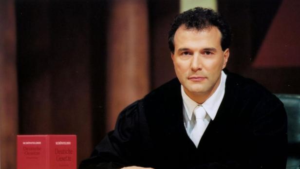 Ein Mann in Robe sitzt vor zwei Ausgaben der „Deutschen Gesetze“.