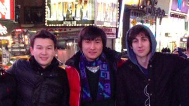 Drei junge Männer posieren vor den Lichtern des Times Square in New York.