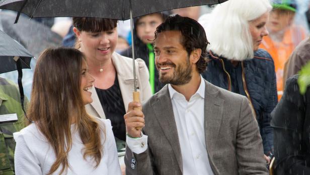 Prinz Carl Philip und Prinzessin Sofia unter einem Regenschirm bei einer Veranstaltung.